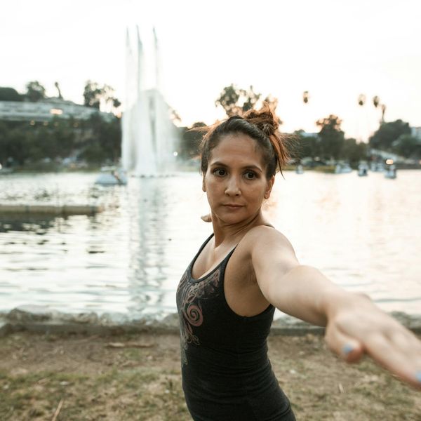 Person holding a difficult balance yoga pose outdoors at sunset.
